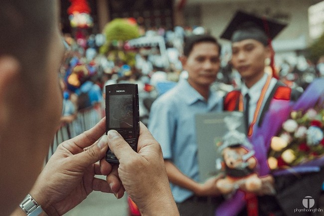 Bức ảnh cảm động: Cái ôm đầy tình cảm trong lễ tốt nghiệp và chiếc điện thoại của cha - Ảnh 2.