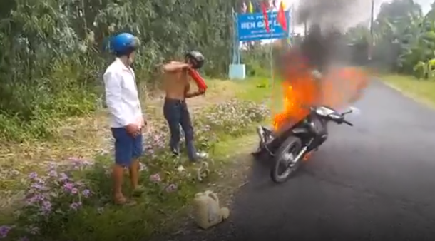 3 thanh niên loay hoay nhìn xe máy bị lửa thiêu rụi vì không mở được bình cứu hỏa - Ảnh 1.