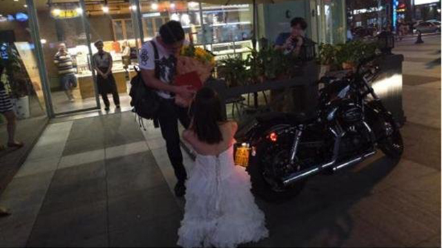 Cô gái mặc váy cưới trắng, cưỡi motor, cầm sổ hộ khẩu cầu hôn bạn trai ngay giữa quảng trường - Ảnh 1.