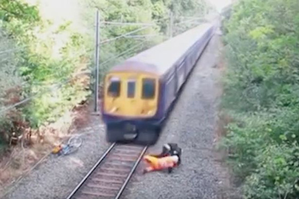 Nhân viên đường sắt dũng cảm lao mình cứu người khi đoàn tàu ầm ầm đi tới - Ảnh 1.