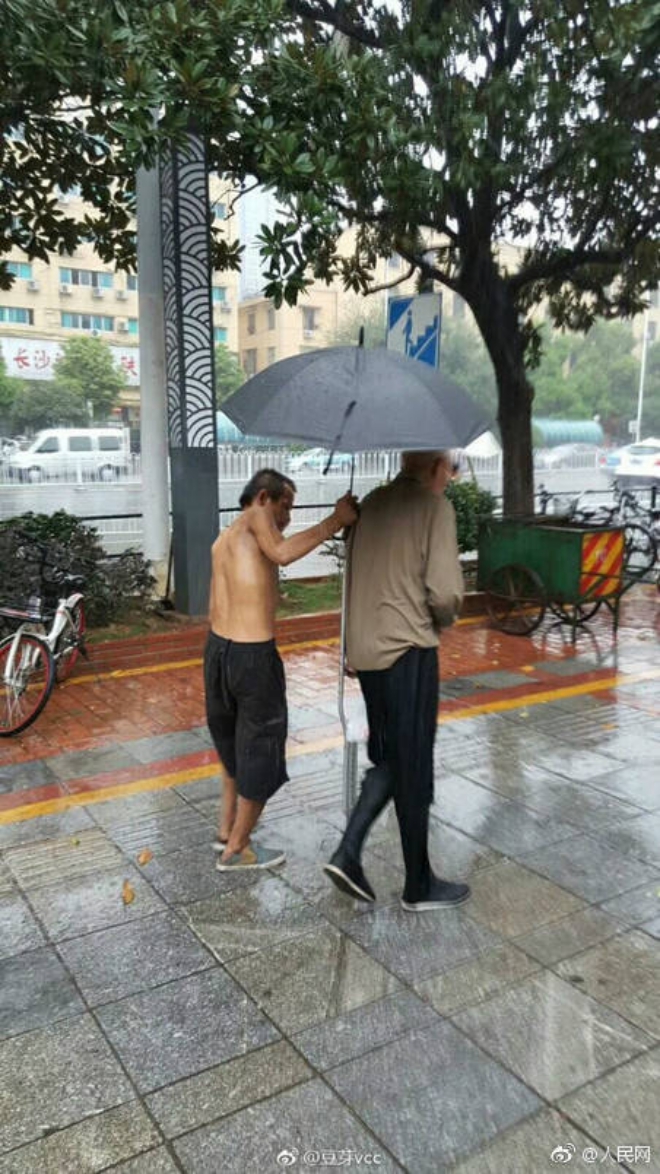 Người ăn m&agrave;y khuyết tật tận tuỵ che &ocirc; cho cụ gi&agrave; chống nạng tập tễnh bước đi trong mưa g&acirc;y x&uacute;c động mạnh - Ảnh 1.