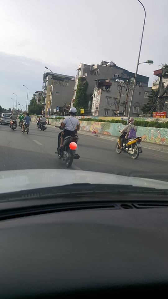 Người phụ nữ trẻ một tay bế con, một tay vẫn điều khiển xe m&aacute;y tr&ecirc;n đường - Ảnh 2.