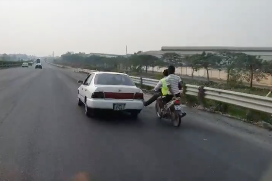 Bàn chân vàng trong làng cứu hộ: Nam thanh niên đi xe máy dùng chân không đẩy ô tô chạy băng băng trên cao tốc - Ảnh 2.
