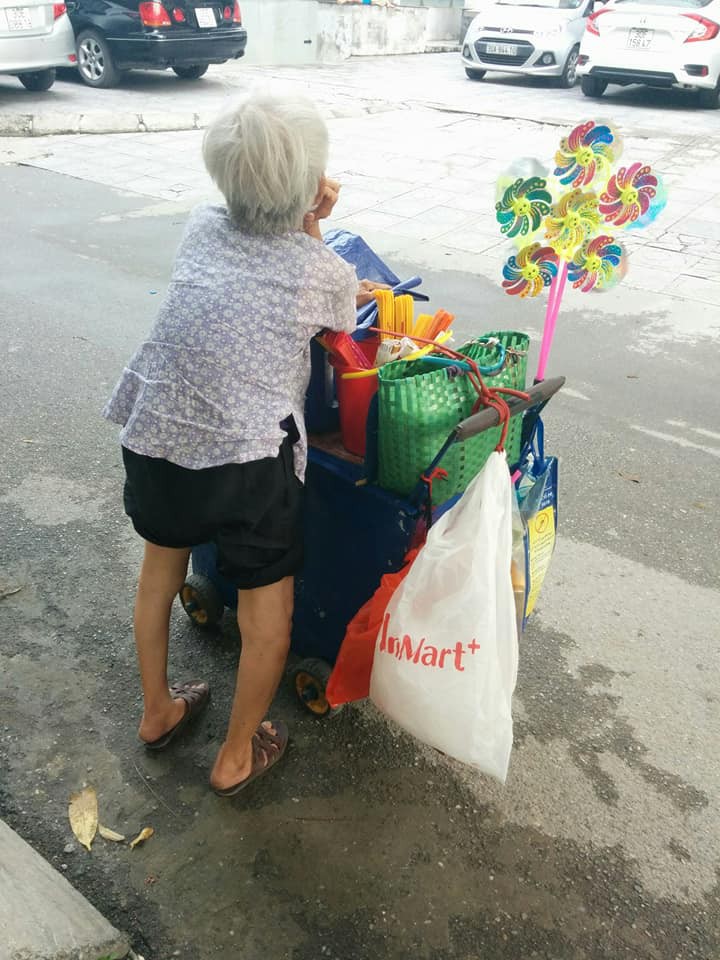 H&igrave;nh ảnh cụ b&agrave; lưng c&ograve;ng gục đầu b&ecirc;n g&aacute;nh h&agrave;ng rong giữa ng&atilde; tư H&agrave; Nội khiến nhiều người x&oacute;t xa - Ảnh 4.