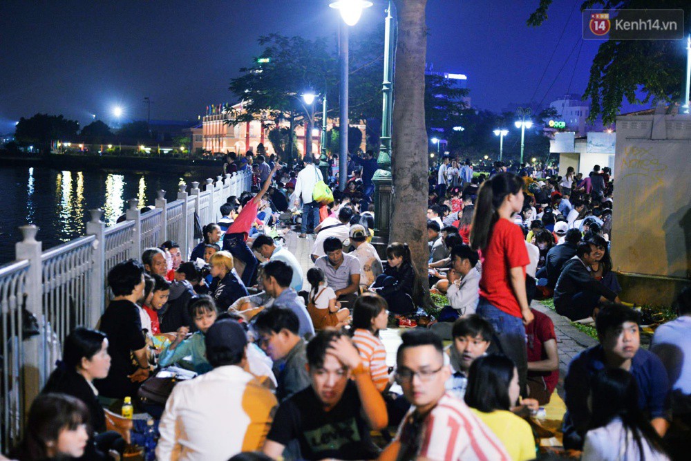 Chùm ảnh: Người lớn trẻ nhỏ trải bạt nằm la liệt bên bến Bạch Đằng chờ xem pháo hoa giao thừa năm mới Mậu Tuất 2018 - Ảnh 1. Dọc bến Bạch Đằng bắt đầu chật kín người ngồi la liệt, không còn chỗ trống