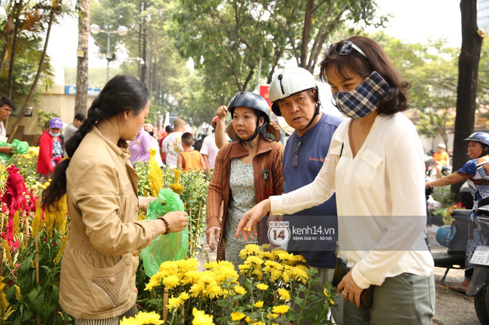 Clip: Không bán hết hàng trưa 30 Tết, nhiều tiểu thương tự tay đập nát chậu hoa, vứt vào thùng rác - Ảnh 4. Một số người dân đứng chọn lựa mặc cả để mua hoa cúc