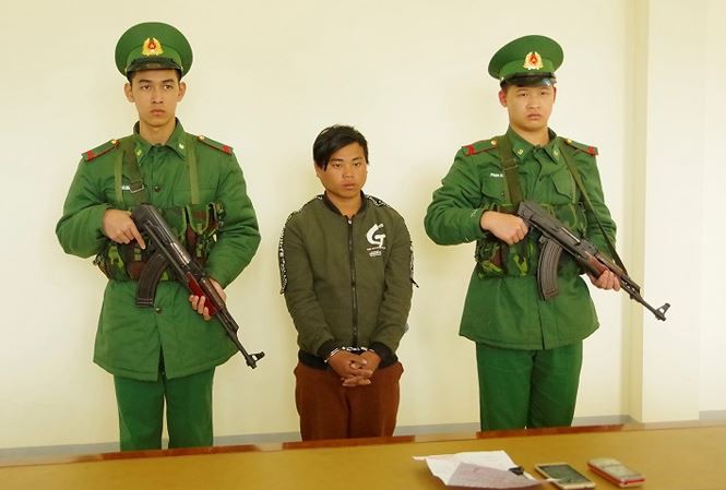Bán người yêu lấy tiền mua xe máy - Ảnh 1. Sùng Seo Tráng (giữa) nghe đọc lệnh bắt tại Đồn Biên phòng Cửa khẩu quốc tế Lào Cai