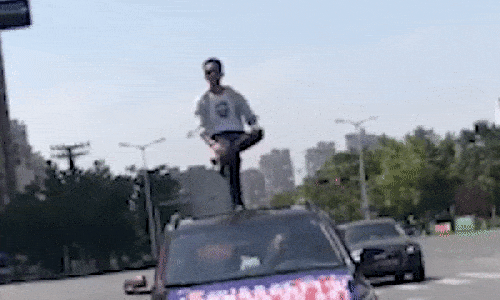 Người đàn ông bị cảnh sát triệu tập vì biểu diễn đứng một chân trên nóc ô tô - Ảnh 1.