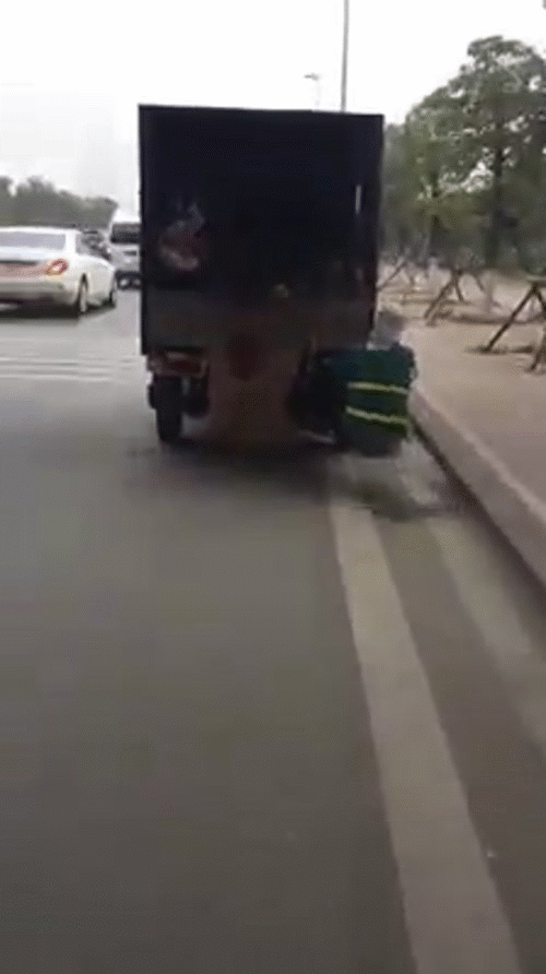 Clip: Người phụ nữ mặc &aacute;o c&ocirc;ng nh&acirc;n vệ sinh m&ocirc;i trường b&aacute;m đu&ocirc;i &ocirc; t&ocirc;, vừa đi vừa nhặt r&aacute;c b&ecirc;n đường nhanh thoăn thoắt - Ảnh 2.