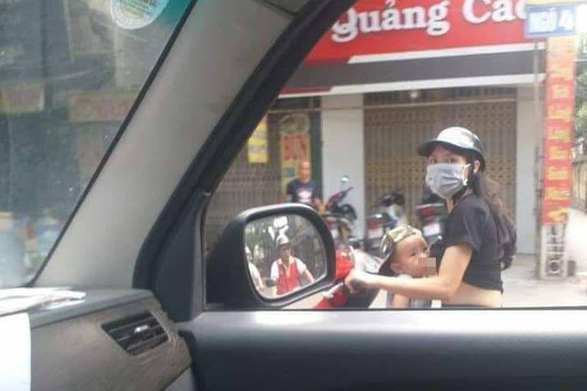 Mẹ trẻ Hà Nội vừa đi xe máy vừa thản nhiên vạch áo cho con bú khiến nhiều người nóng mắt - Ảnh 1.