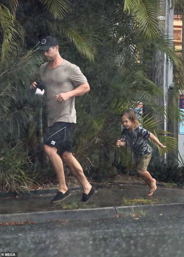 Ông bố phũ của năm: Cùng dầm mưa nhưng Thor Chris Hemsworth đội mũ đi giày, để con trai đầu trần chân đất - Ảnh 1.