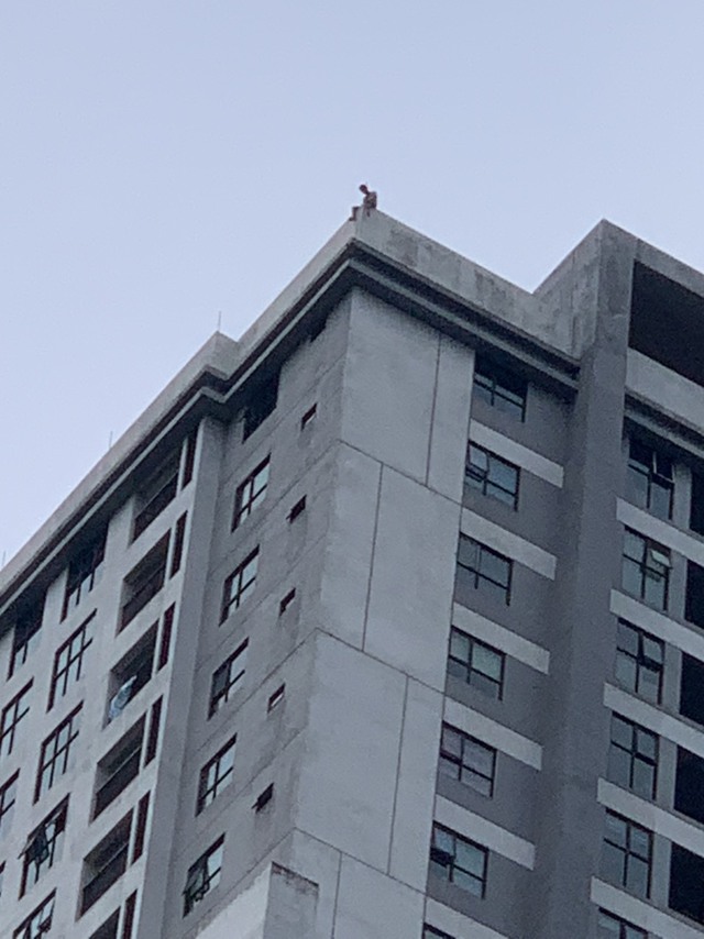 Người đàn ông nằm vắt vẻo trên nóc chung cư 40 tầng, định tự tử - Ảnh 1.