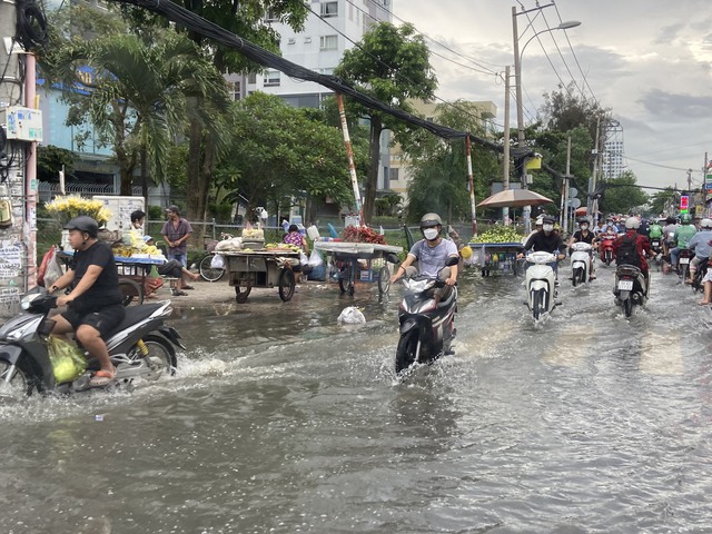 TP.HCM: Triều cường dâng cao 1,5m, người dân bì bõm trên đường ngập nước - Ảnh 4.