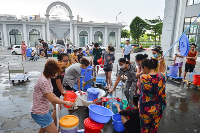 Ảnh: Người dân chung cư Hà Nội mang xô chậu đi lấy nước sạch để rửa bát, tắm gội - Ảnh 1.