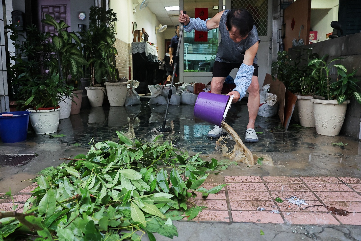 A man cleans the flood inside his home after Typhoon Krathon made landfall in Kaohsiung