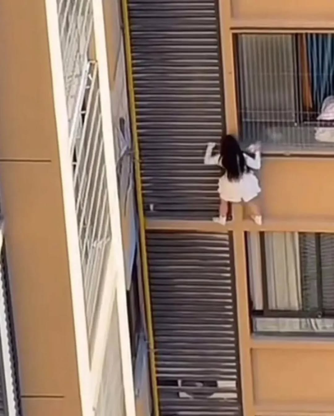 Clip cô gái trèo ra khỏi cửa sổ chung cư, bùng nổ tranh cãi khi zoom cận phát hiện người đàn ông cởi trần- Ảnh 1. Clip cô gái trèo ra khỏi cửa sổ chung cư, bùng nổ tranh cãi khi zoom cận phát hiện người đàn ông cởi trần- Ảnh 1.