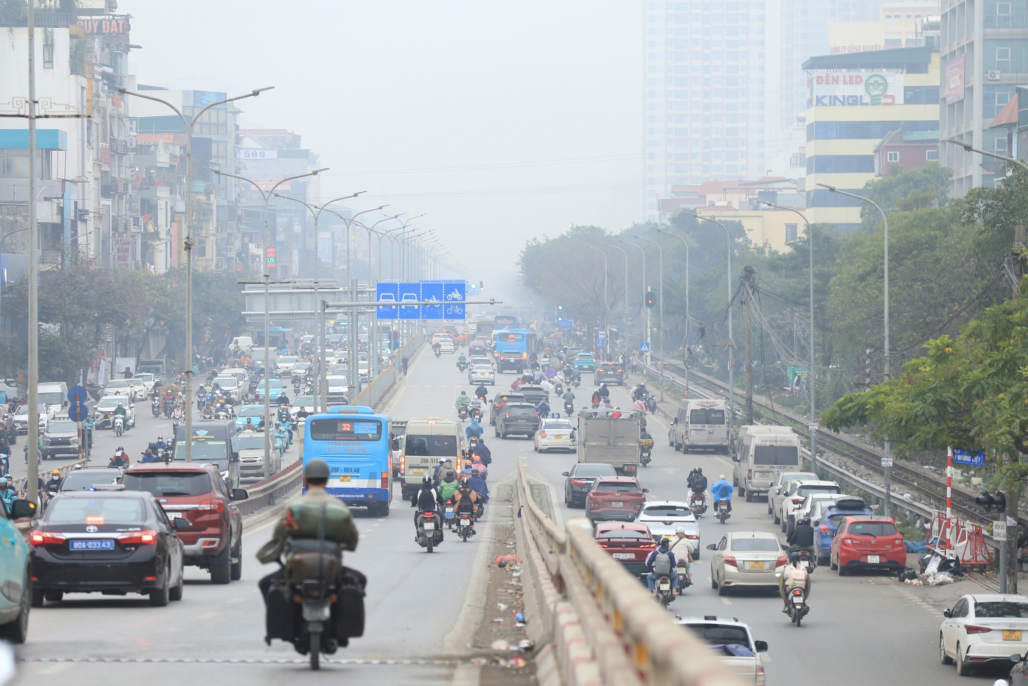 Hà Nội chìm trong sương mù và bụi mịn, nhiều người tham gia giao thông phải bật đèn xe giữa ban ngày vì tầm nhìn hạn chế- Ảnh 1.