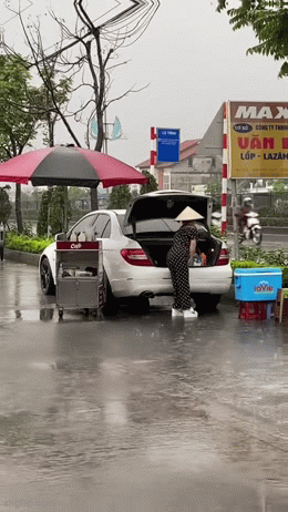 Hành động lạ bên cạnh chiếc ô tô của người phụ nữ bán nước dưới cơn mưa nặng hạt khiến dân mạng đứng hình- Ảnh 1.