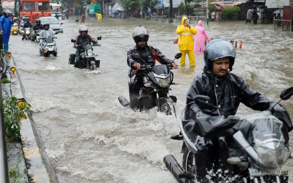 Người dân đi xe máy qua tuyến đường ngập nước trong mưa lớn ở Mumbai, Ấn Độ, ngày 18/8/2025 (Ảnh: AP/Rajanish Kakade)