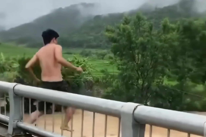 VIDEO: Người đàn ông bất ngờ trèo lan can cầu, lao xuống dòng nước lũ chảy xiết- Ảnh 1.