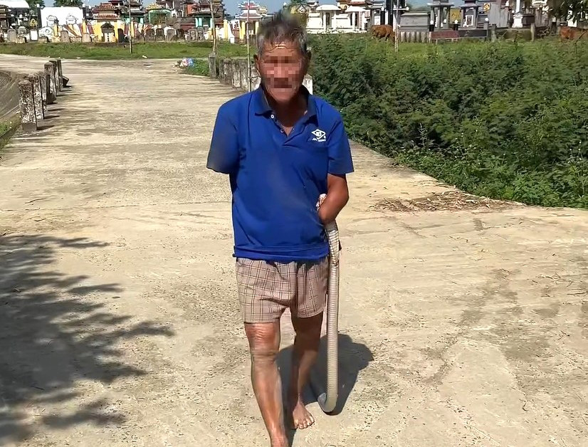 Cụ &ocirc;ng kẹp chặt rắn hổ mang tr&ecirc;n tay đi giữa đường khiến nhiều người hoảng hốt: Người nh&agrave; lập tức đưa đi cấp cứu ngay sau đ&oacute;- Ảnh 1.