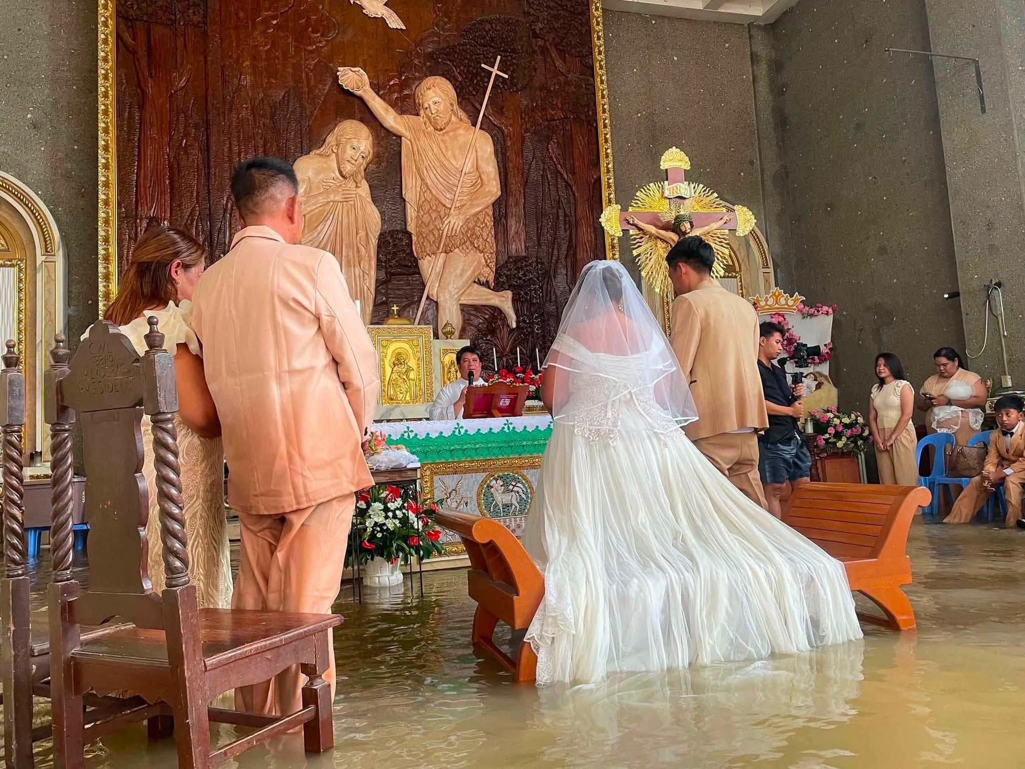 Nhà thờ ngập đến eo, cô dâu vẫn quyết mặc váy cưới lội nước bước vào lễ đường- Ảnh 2.