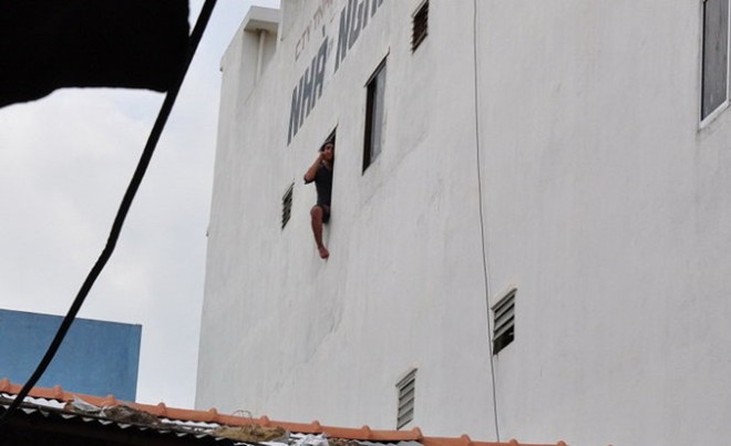 Nam thanh niên đang ngồi ở tầng 3 của nhà nghỉ Trùng Dương đòi nhảy lầu tự tử - Ảnh: Tấn Vũ 