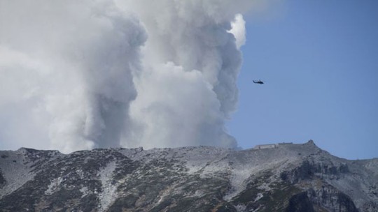 Trực thăng tham gia cứu hộ trên núi trong khi núi lửa vẫn phun bụi tro. Ảnh: AP