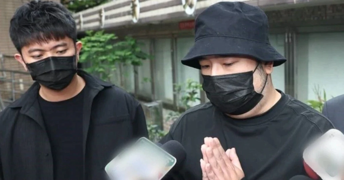 出廷し、黒い帽子とマスク姿で手を合わせる唐禹哲(右)と男性