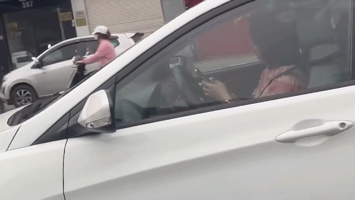 Nữ tài xế dùng 2 tay bấm điện thoại trong lúc đang lái xe trên phố Hà Nội