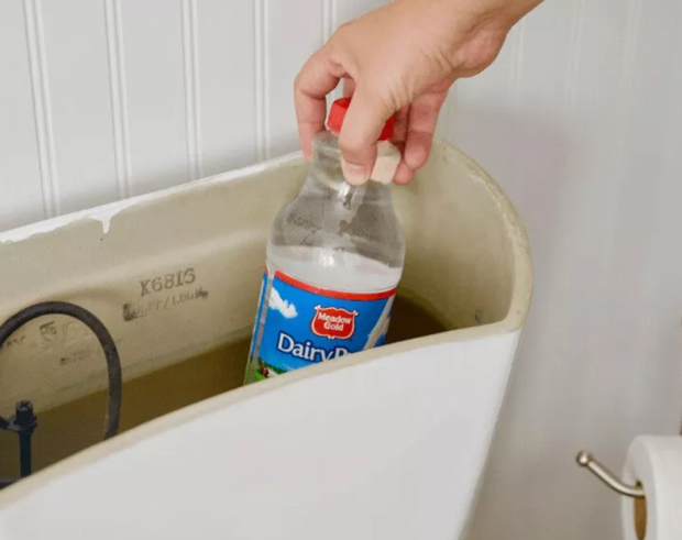 What does placing a plastic bottle in the toilet tank do?