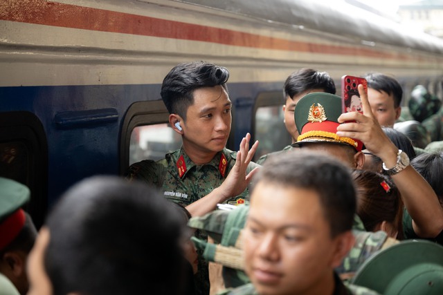 Thượng úy Lê Hoàng Hiệp được các chiến sĩ khác “hộ tống” di chuyển ra khỏi vòng vây của đông đảo người dân tại ga Hà Nội- Ảnh 3.