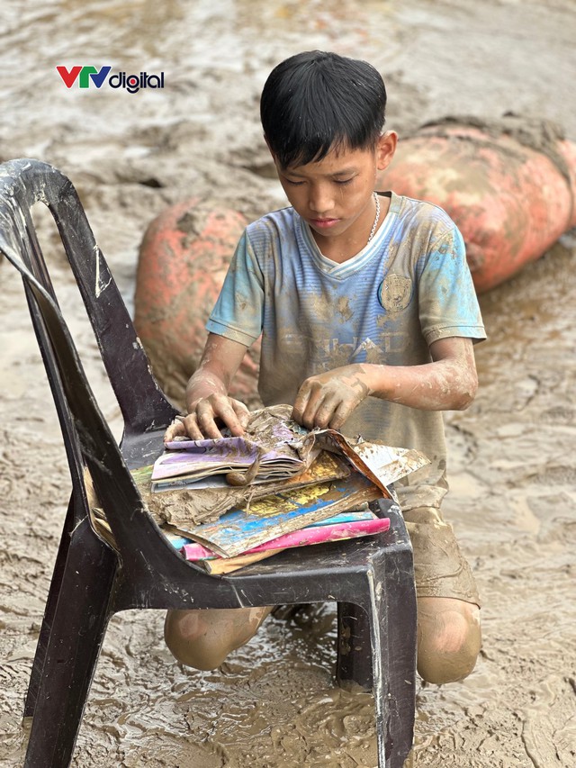 Cậu bé 12 tuổi lật từng trang sách lấm bùn sau lũ quét ở Nghệ An: “Chữ vẫn còn đọc được cô ạ!”- Ảnh 1.
