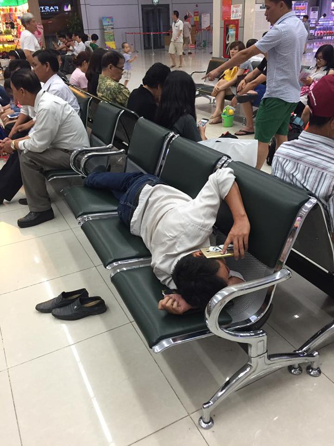 H&igrave;nh ảnh ph&aacute;t ngượng ở s&acirc;n bay Nội B&agrave;i: Người đ&agrave;n &ocirc;ng nằm d&agrave;i ra ghế nấu ch&aacute;o điện thoại - Ảnh 2.