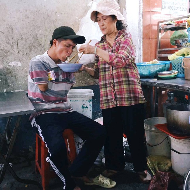 Khoảnh khắc đẹp ở Sài Gòn: Cô chủ quán đút từng miếng bún cho anh bán vé số cụt hai tay - Ảnh 1.