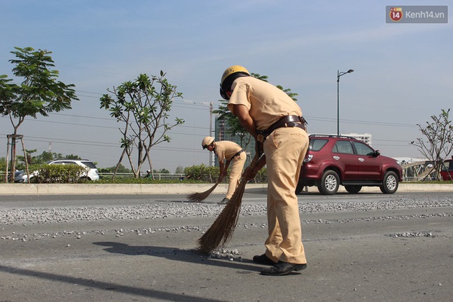 CSGT Sài Gòn đội nắng quét dọn đá rơi trên đại lộ giúp người dân - Ảnh 1.