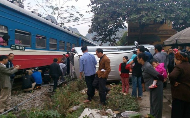 Cố vượt đường t&agrave;u, &ocirc; t&ocirc; 7 chỗ bị t&ocirc;ng lật nghi&ecirc;ng, 2 người tho&aacute;t chết trong gang tấc - Ảnh 1.
