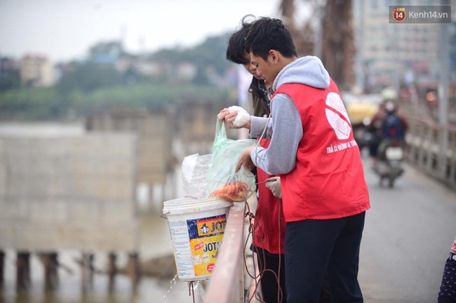 Nhiều bạn trẻ tất bật giúp người dân thả cá và gom đồ phóng sinh trong ngày ông Công ông Táo - Ảnh 1.