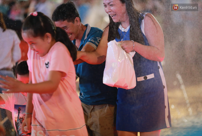 Người lớn, trẻ nhỏ nhảy vào đài phun nước ở đường hoa Nguyễn Huệ để vui đùa đêm Giao Thừa - Ảnh 3.