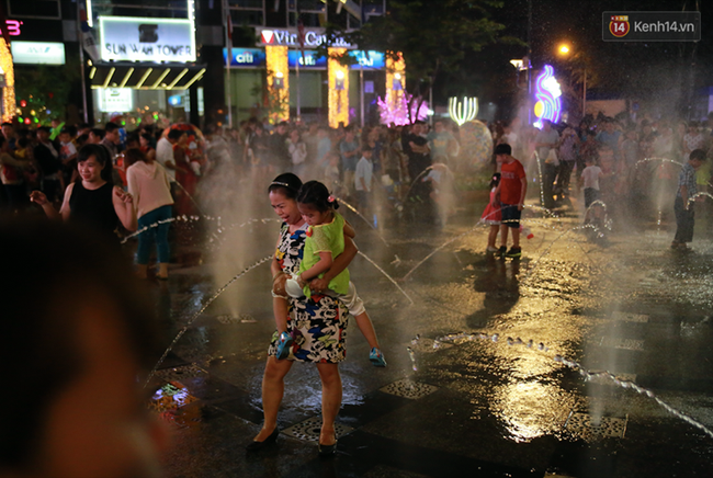 Người lớn, trẻ nhỏ nhảy vào đài phun nước ở đường hoa Nguyễn Huệ để vui đùa đêm Giao Thừa - Ảnh 7.