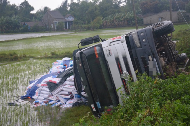 Quảng Nam: Mưa gió lớn, xe tải chở 20 tấn thức ăn gia súc mất lái lật xuống ruộng - Ảnh 2.