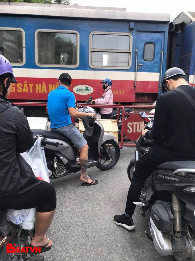 Bức ảnh gây căng thẳng: Cô gái đi xe máy đứng trong khe hẹp giữa đoàn tàu đang chạy và rào chắn - Ảnh 1.