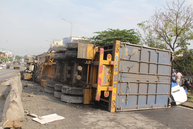 Xe container mất lái bị lật nghiêng giữa QL1A, người dân giúp tài xế thu gom hàng hóa đổ ra đường - Ảnh 1.