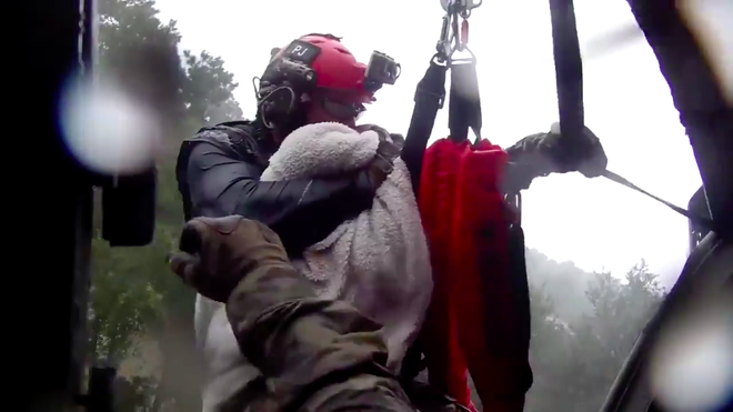 Trực thăng kéo nhân viên cứu hộ khỏi dòng lũ, thứ mà ông ôm chặt khi làm nhiệm vụ khiến nhiều người rơi nước mắt - Ảnh 2.