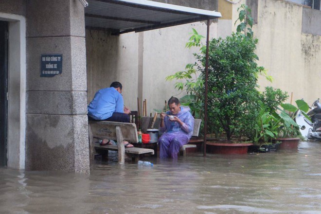 Chùm ảnh: Người Hà Nội mặc áo mưa ăn trưa giữa đường phố ngập lênh láng - Ảnh 2.