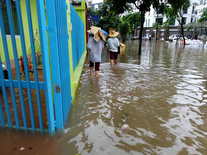 Chùm ảnh: Người Hà Nội mặc áo mưa ăn trưa giữa đường phố ngập lênh láng - Ảnh 8.