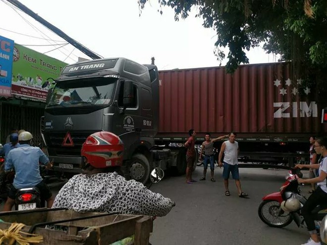 Bất chấp nguy hiểm, người d&acirc;n thi nhau chui gầm container chắn ngang giữa đường để lưu th&ocirc;ng - Ảnh 1.