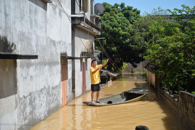 Chùm ảnh: Nhà ngập sâu đến ngang cửa, người dân Ninh Bình dùng chậu nhôm, ghế gỗ chèo thuyền đi lại trong ngõ - Ảnh 2.