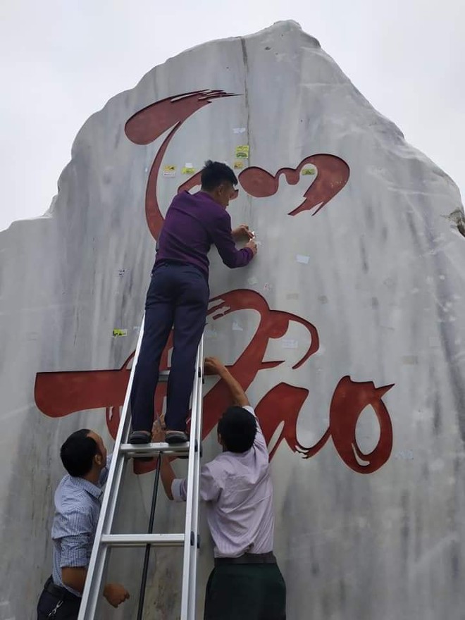 Tấm bia đá nổi tiếng Tam Đảo bị dán quá nhiều logo phượt khiến người dân phải bắc thang lên bóc - Ảnh 1.