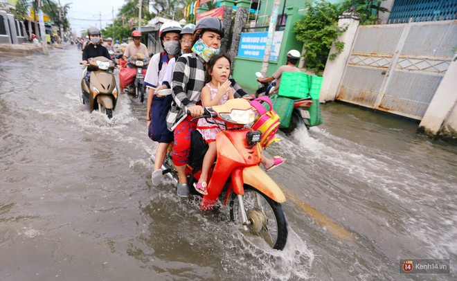 Triều cường dâng cao ở Sài Gòn, cha mẹ khổ sở đẩy xe lội nước đưa con đi học về - Ảnh 2.